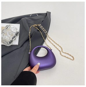 Detail of purple matte acrylic handbag with curved handle and fine gold chain strap