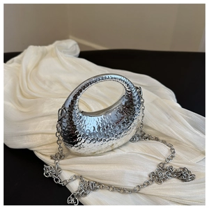 Detail of silver crescent handbag with hammered metal texture and detachable chain strap