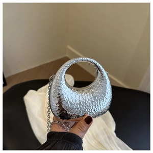 Detail of silver evening clutch with hammer-textured finish and round hollow handle