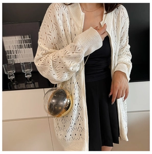 Detail of a modern spherical transparent metal bag with a chic white knitted cardigan