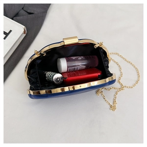 Detail view of the blue textured clutch bag showing interior space and golden chain strap
