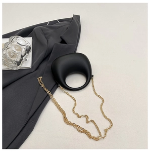 Minimalist black matte irregular handbag with circular handle and gold chain strap detail