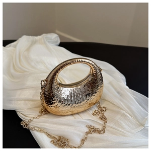 Detailed view of gold crescent clutch with hammered texture and integrated round handle