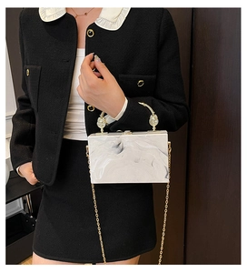 Detail of white marble acrylic clutch bag with gold metal handle and chain strap