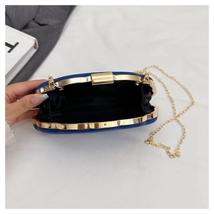 Detail view of the open dark blue leather evening bag with golden clasp and chain strap