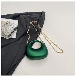Detail of dark green pearlescent acrylic handbag with elegant gold metal chain strap