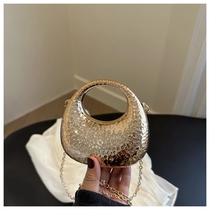 Detailed close-up of golden crescent evening bag featuring a unique hammered metal texture