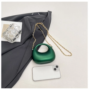 Detailed view of a dark green semi-circular chain bag with a gold metal strap and handle
