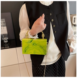 Detail of green marble acrylic box bag with gold ring handle and metal chain strap
