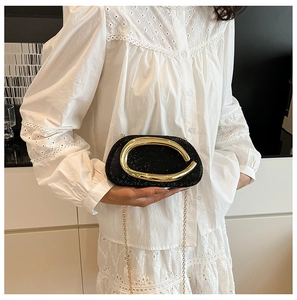 Close-up of black rhinestone evening clutch with gold metal handle and chain strap