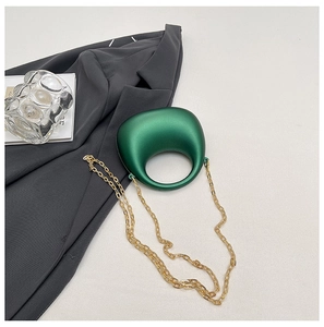 Detail of emerald green organic handbag with metallic finish and gold chain strap