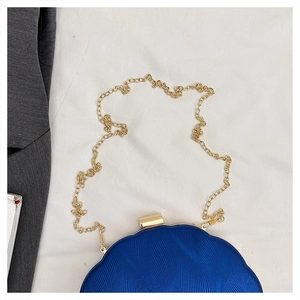 Detail of blue shell evening bag with wavy texture and golden chain strap