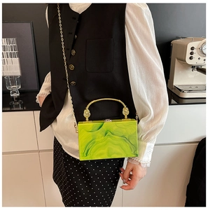 Detail of green marble acrylic clutch with elegant gold metal handle and chain strap