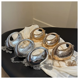 Detail view of mini gold and silver evening bags with metallic texture on silk fabric