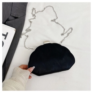 Detail of black clutch evening bag with wave texture and silver chain strap