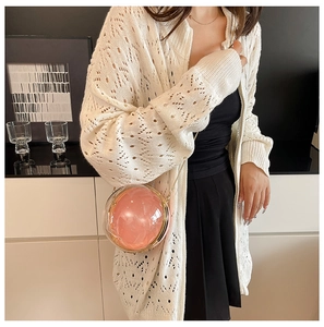 Detail of spherical acrylic bag with pink lining and gold chain strap on model