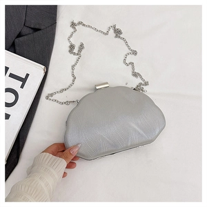 Detail of silver shell-shaped evening bag with pleated texture and metal chain
