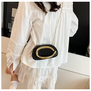 Close-up of black crossbody bag with metallic texture, golden ring buckle, and chain strap