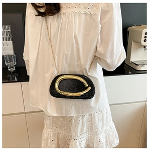 Detail of elegant black glitter evening bag with golden C-handle and metal chain strap