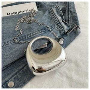Detailed close-up of a silver crescent mini bag with metallic mirror finish and chain strap