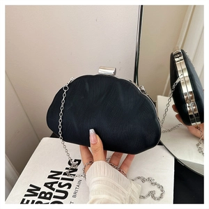 Detailed close-up of a black pleated clutch bag with silver metal lock and chain strap