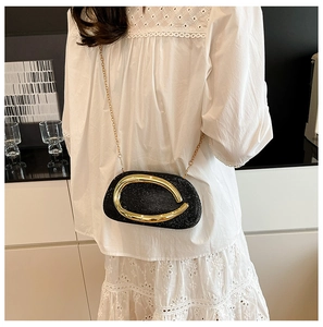 Detail of black glitter evening clutch with oversized gold metal ring and chain strap