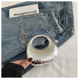 Detail of silver crescent bag with textured hammered finish and metallic chain strap