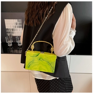 Detail of green marble acrylic box bag with golden metal handle and chain strap