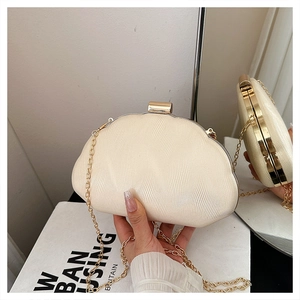 Detail of light beige shell evening clutch with pearlescent wave texture and gold chain