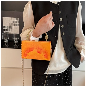 Detail of orange marble acrylic handbag with gold metal ring handle and chain strap