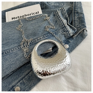 Detail view of the silver metallic crescent bag with handcrafted hammered texture and chain