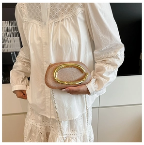 Detail view of a rose gold glitter evening clutch bag with a gold C-shaped metal handle