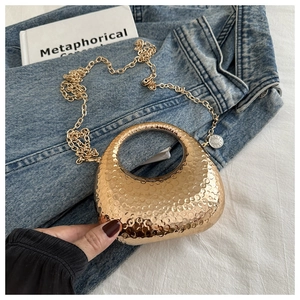 Detailed close-up of gold crescent mini bag with hammered metal texture and ring handle