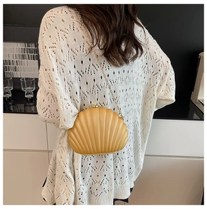 Chic yellow shell-shaped crossbody bag with gold chain strap shown on a model