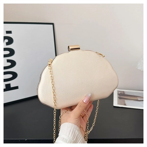 Detail of cream shell-textured clutch with gold metal frame and fine chain strap