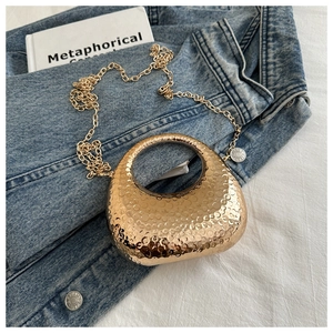 Detail of gold crescent evening bag with hammered metal texture and gold chain strap