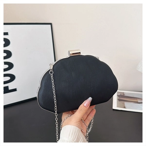 Detail of black shell-shaped evening clutch with pleated texture and silver chain strap