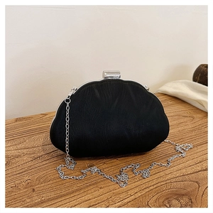 Detail of black evening clutch bag with wave texture and silver chain strap