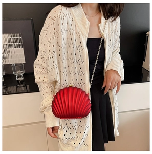 Close-up of red shell-shaped evening clutch bag with golden chain strap and ribbed texture