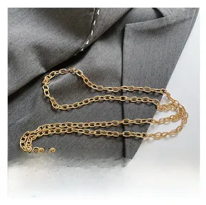 Close-up of premium gold metal chain strap on textured gray suit fabric background