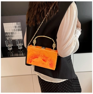 Detail of orange marble acrylic handbag with gold metal handle and chain strap