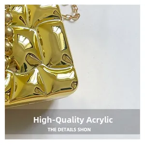Close-up of premium acrylic evening bag with gold geometric relief and bead handle