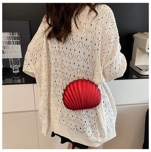 Chic red shell clutch bag with gold chain strap styled on white lace top for a gala