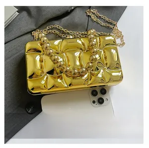 Detail showing metallic gold clutch size comparison with a white smartphone