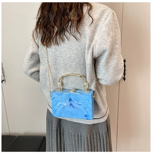 Detail of blue marble acrylic box bag with gold metal handle and chain strap