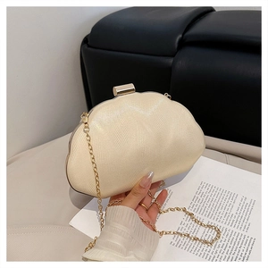 Detail of beige shell-shaped clutch with wave texture and gold chain strap