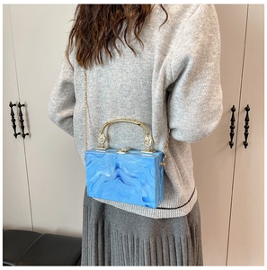 Blue marble acrylic box bag detail featuring gold metal handle and chain shoulder strap