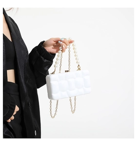 Detail of white acrylic box bag featuring quilted bubble texture and pearl handle