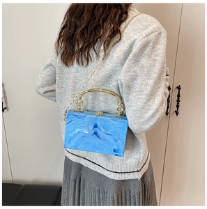 Blue marble acrylic box bag with gold metal handle and chain strap shown on a model