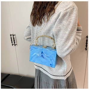 Detail of blue marble acrylic evening bag with gold handle and chain shoulder strap